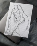 Black and white pencil sketch of two hands holding a ring, placed on a laptop on a dark surface