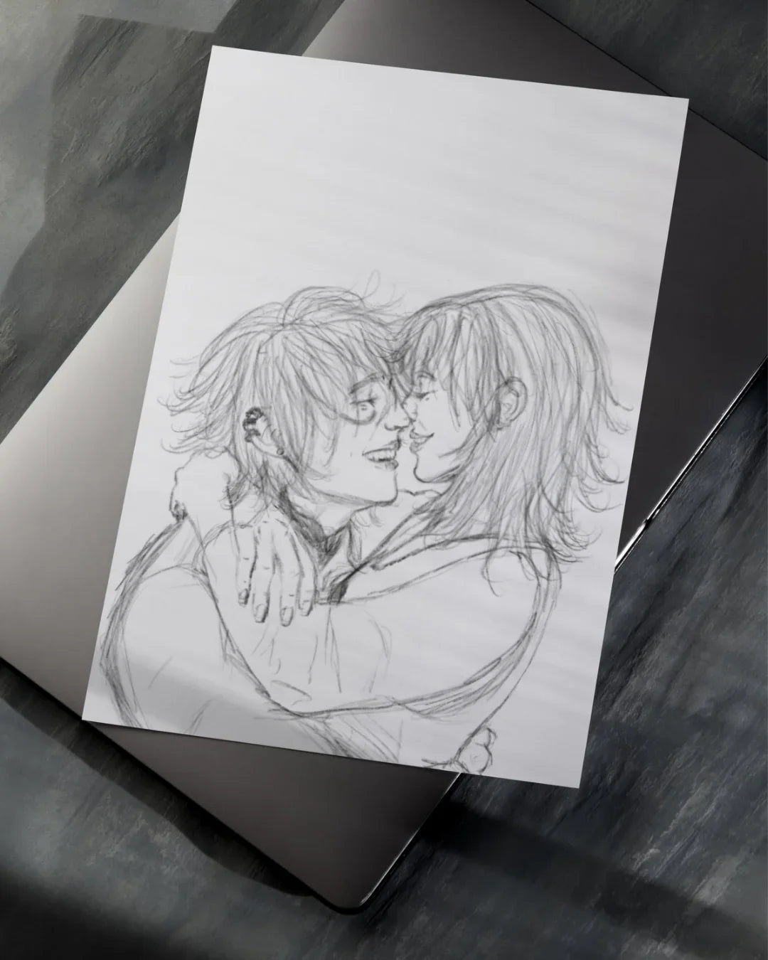 Pencil sketch of two people embracing and smiling, drawn on white paper placed on a laptop